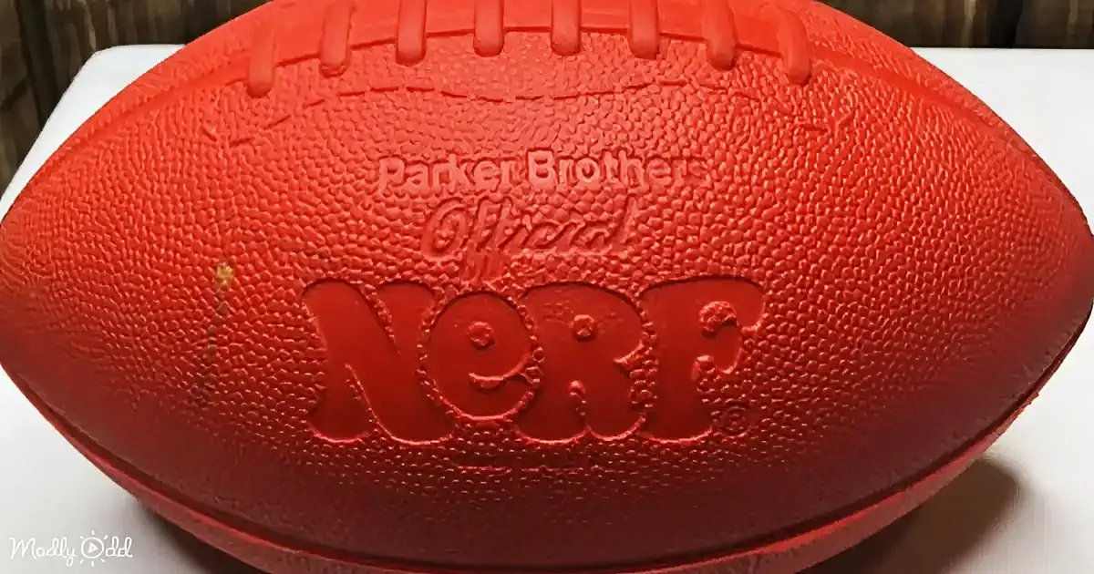 A red Nerf football with "Parker Brothers Official Nerf" embossed on it sits on a white surface.