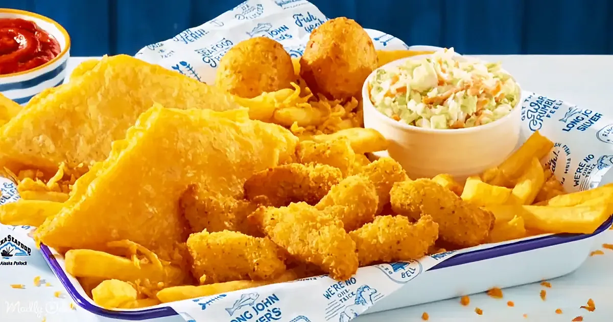 A basket of golden fish and chips with coleslaw and ketchup on the side.