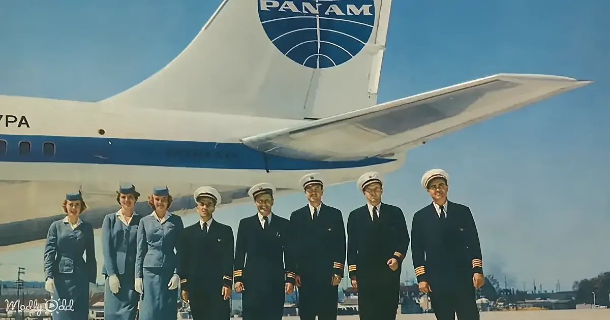 Pilots and flight attendants in uniform stand in front of a Pan Am airplane under a clear sky.