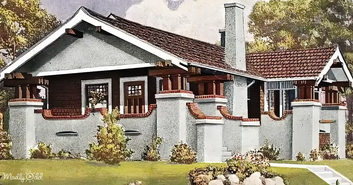 A vintage house with a red-tiled roof, white trim, and brick accents stands amidst a landscaped yard.