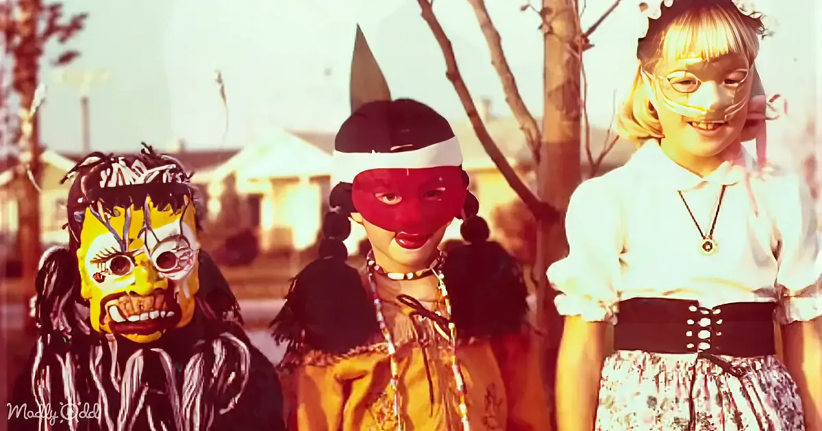 A person in a red mask and costume stands next to another in a yellow mask and costume, with a third person in a white...