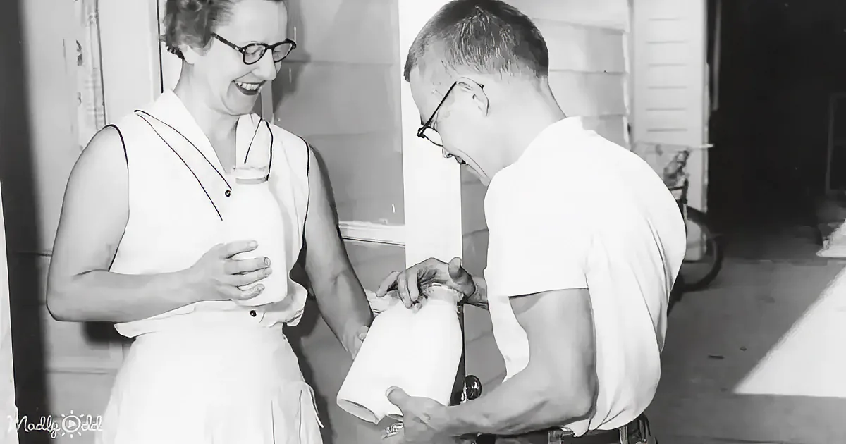 A woman in a white dress holds a cup while a man in a white shirt assists with a roll of paper towels.