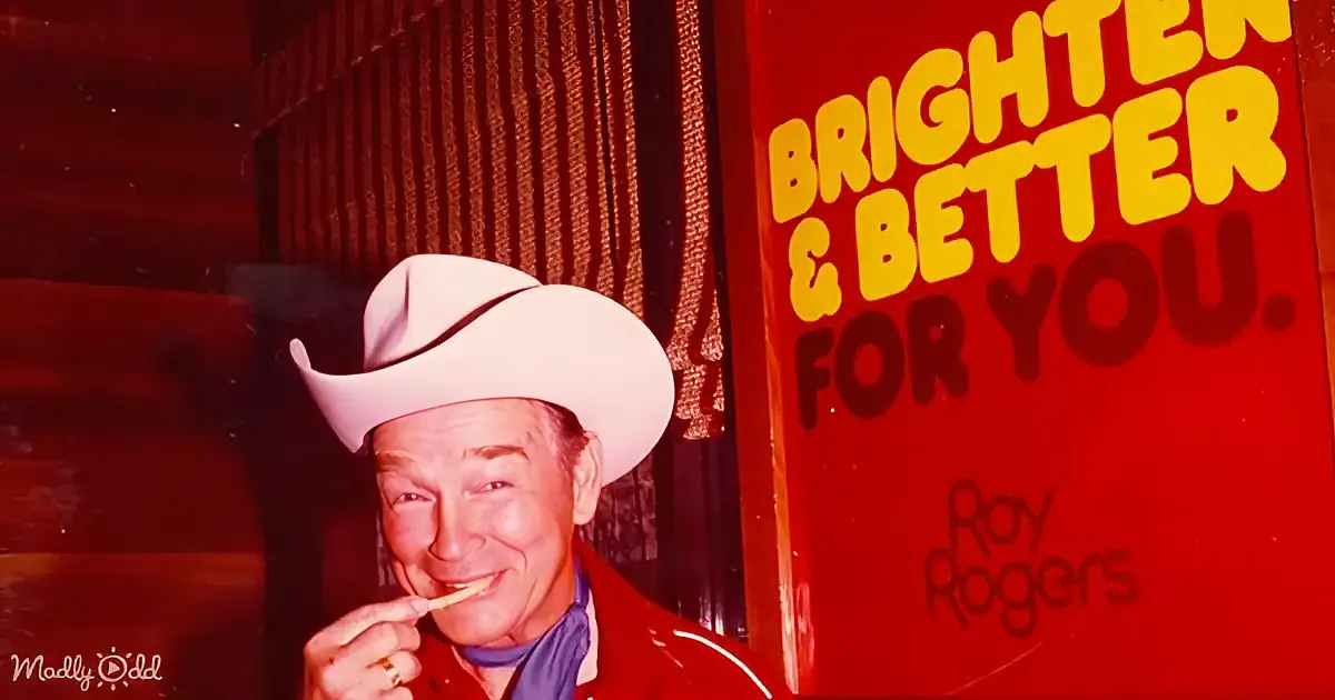 A man in a cowboy hat and red jacket is eating a snack, with a sign behind him reading "Brighter & Better For You."