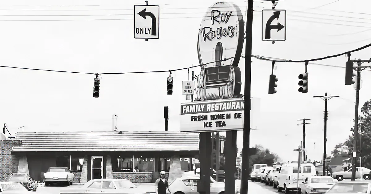 A vintage Roy Rogers restaurant sign with a train and "Family Restaurant" below, surrounded by traffic lights and cars.