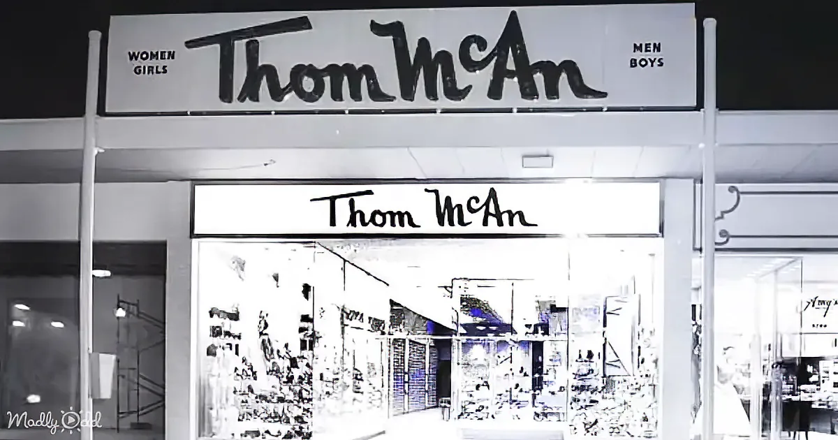 The storefront of Thom McAn, a shoe store, with signage for women/girls and men/boys.