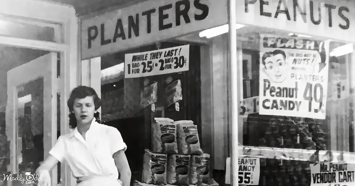 A woman in a white shirt stands in front of a Planters Peanuts store with vintage signage and displays.