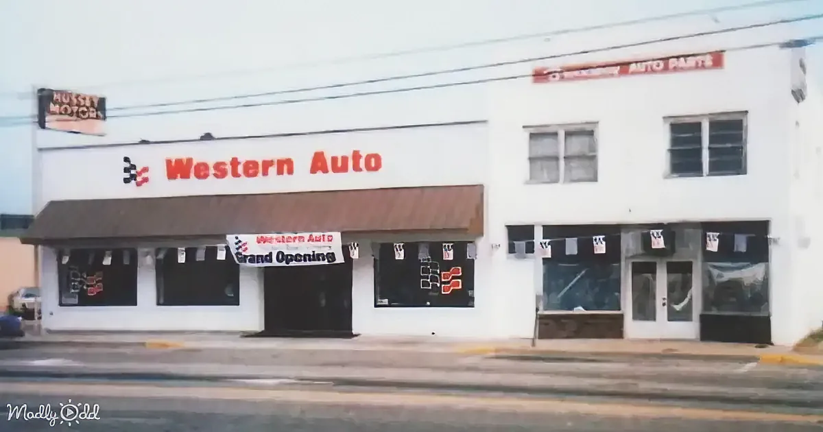 Western Auto storefront with "Grand Opening" banner, white building, and adjacent auto parts sign.