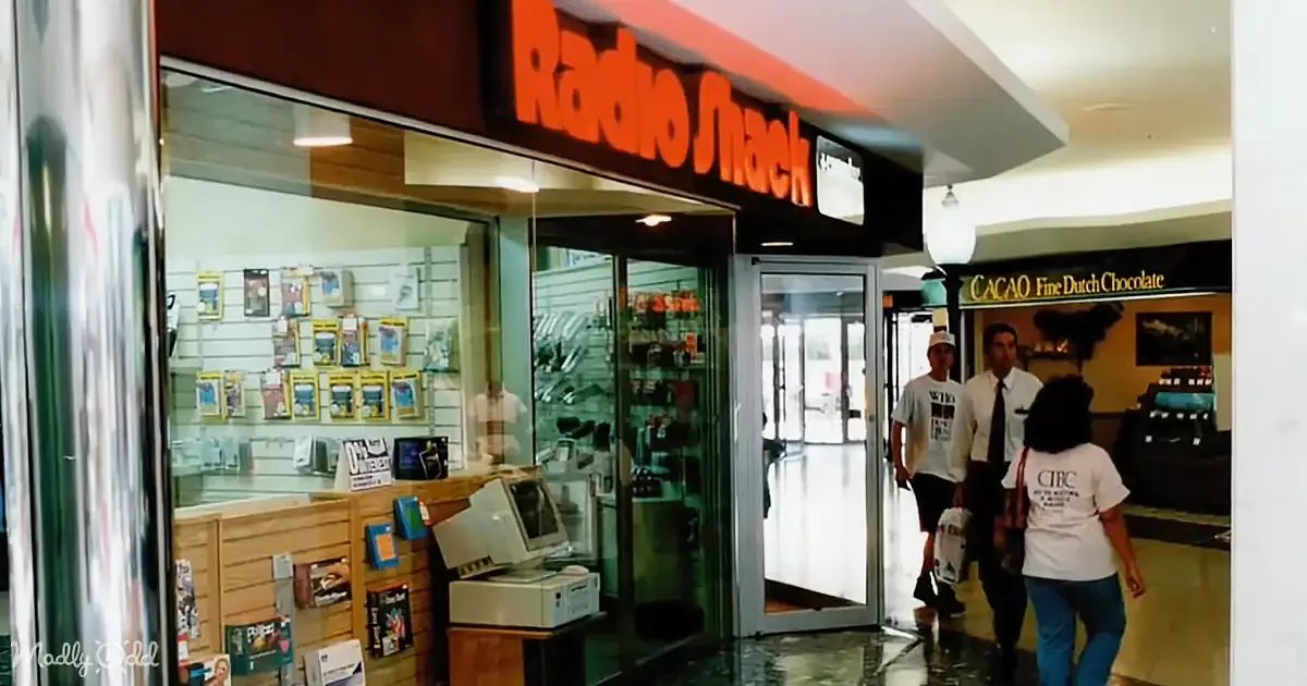 People walk past a Radio Shack store with a computer and other electronics visible inside.