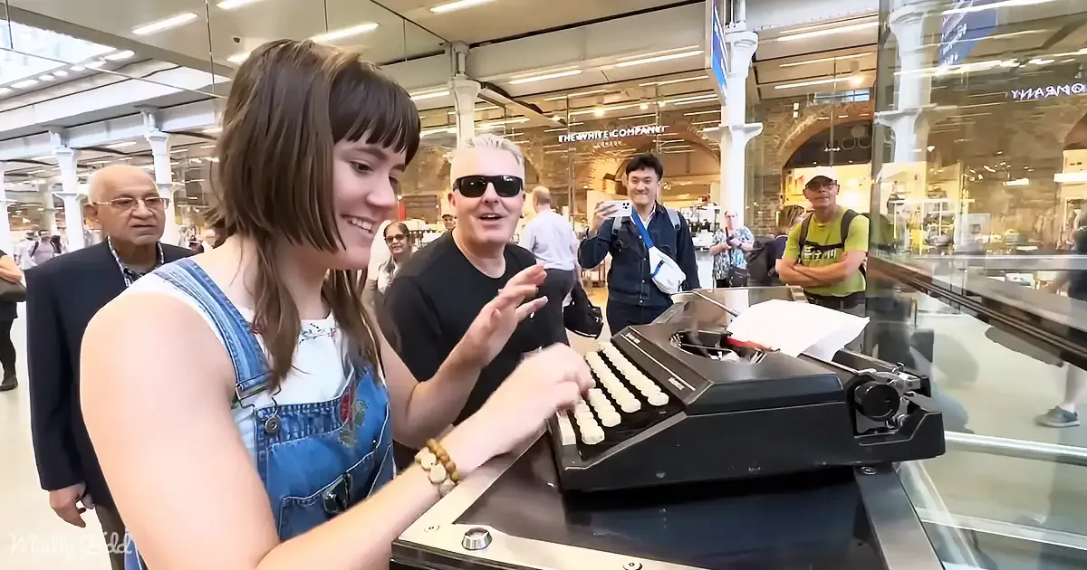 A woman in denim overalls types on a vintage typewriter in a bustling shopping mall.