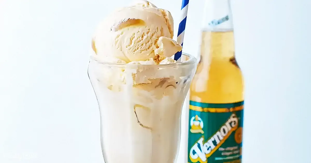 A creamy milkshake with vanilla ice cream and a striped straw sits next to a bottle of Vernors ginger ale.