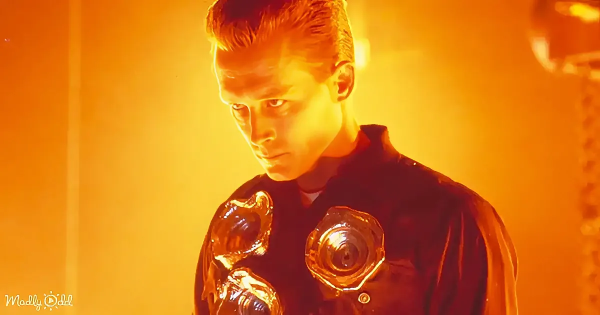 A man in a dark, futuristic outfit with glowing, metallic shoulder pads stands under warm, orange lighting.