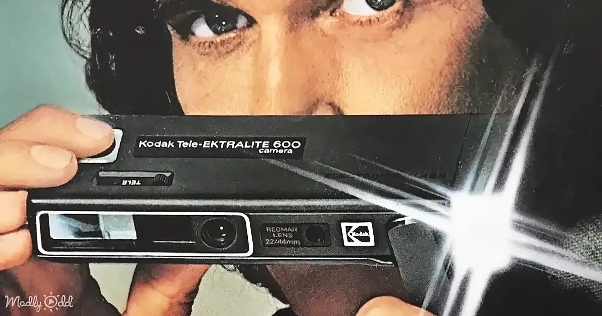 A person holding a Kodak Tele-EKTRALITE 600 camera with a bright flash, partially obscuring their face.