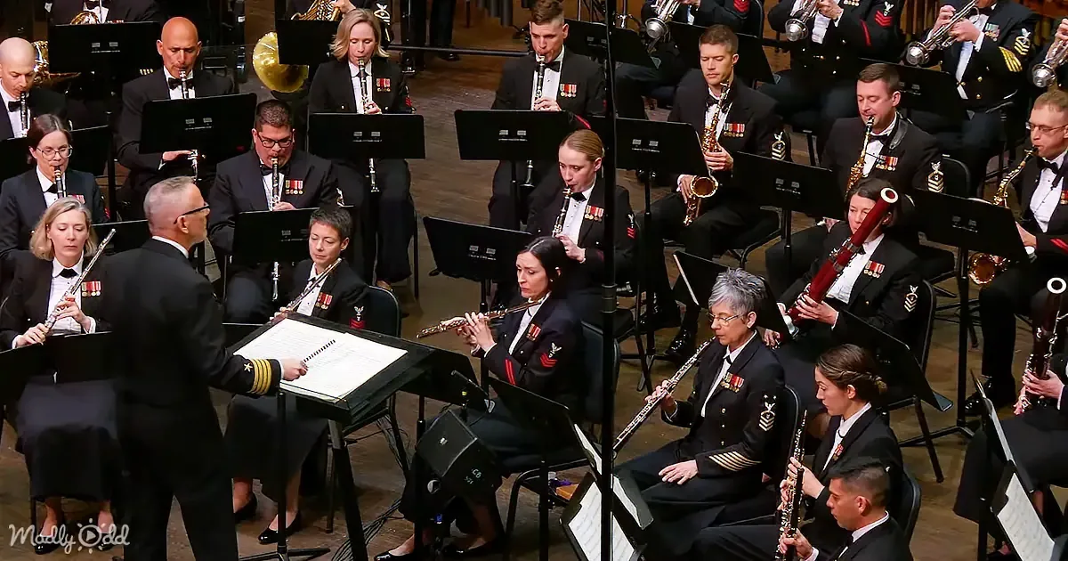 A conductor leads a military band in formal uniforms, playing various instruments.