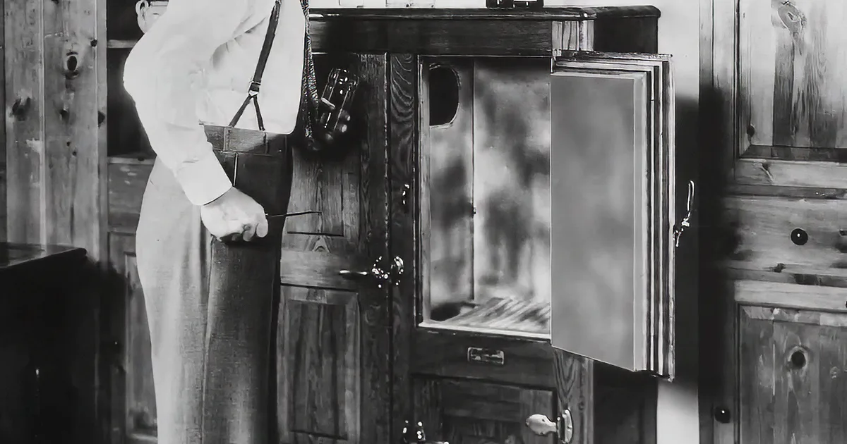 A woman and three children interact with a vintage television in a room with patterned wallpaper.