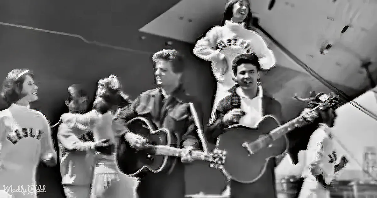 A group of musicians in traditional attire plays guitars and sings, with a woman in a white fur coat standing above them.