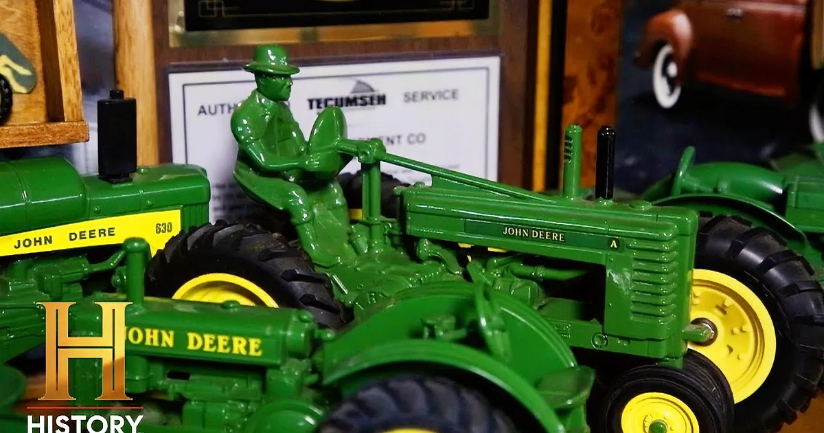 A green John Deere tractor model with a farmer figure on top is displayed, showcasing intricate details and vibrant colors.