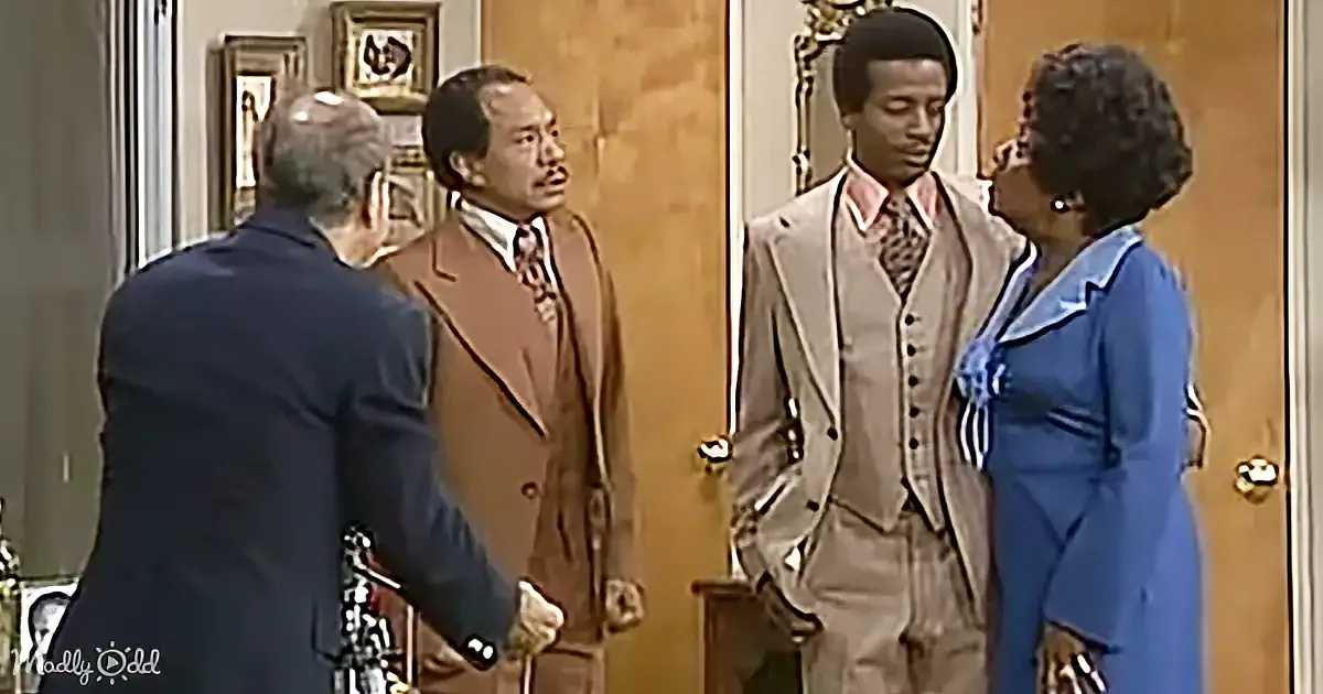 A man in a suit and tie is standing in a doorway, looking at another man in a suit and tie who is leaning forward.