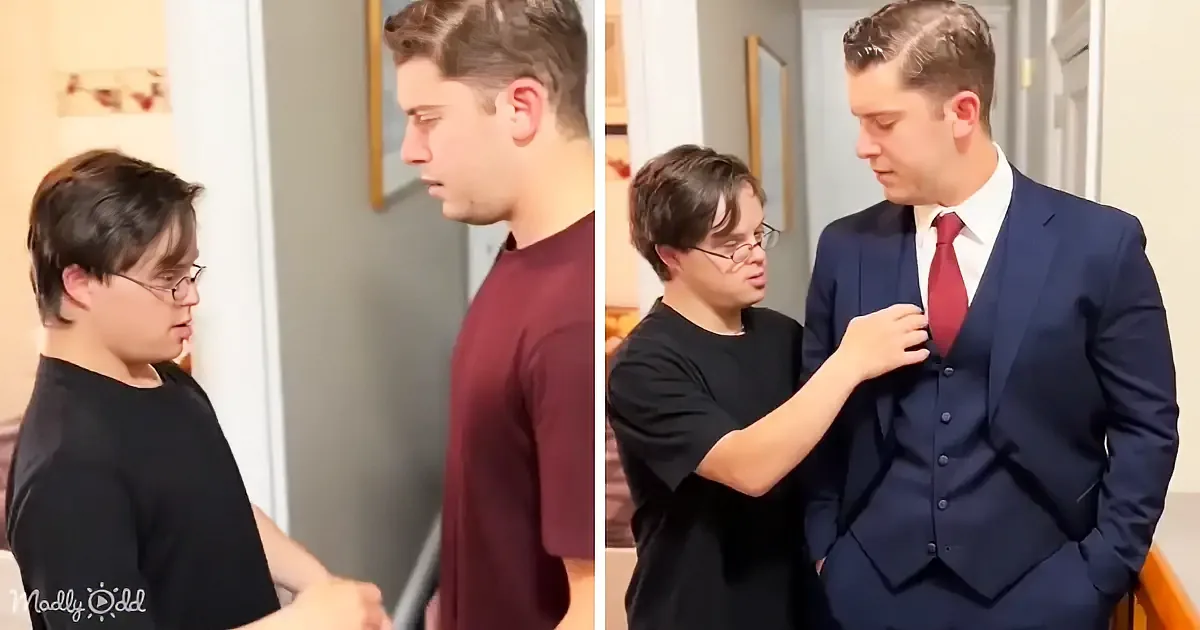 A young man in a suit is being assisted by another young man in adjusting his tie.