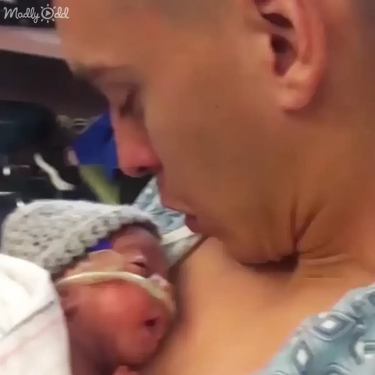 A man is holding a newborn baby wrapped in a blanket, both appearing calm and serene.