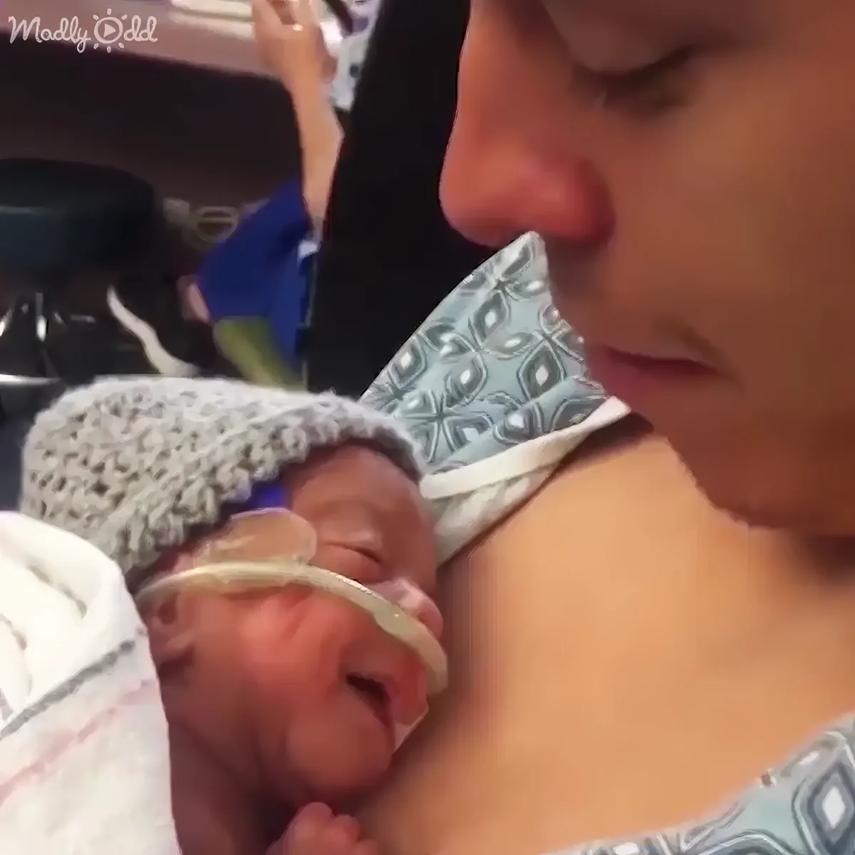 A woman holds a newborn baby wrapped in a blanket, both appearing calm and serene.