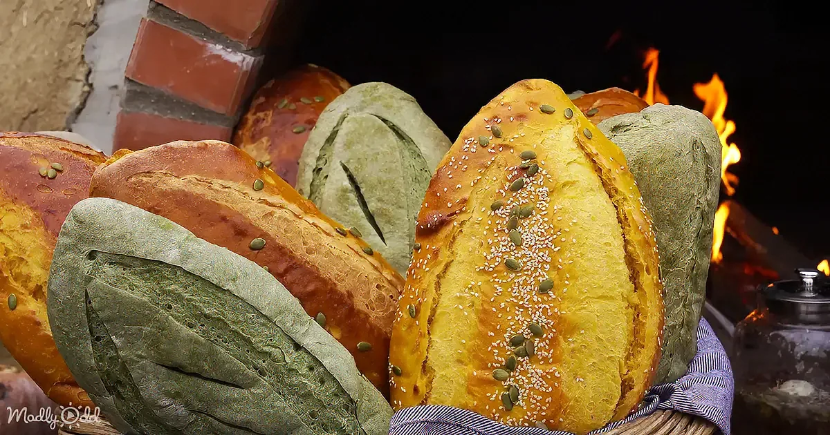 Freshly baked bread with seeds and herbs, placed on a rustic surface near a fire.
