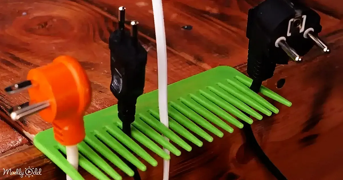 A green comb-like organizer holds three electrical plugs of different colors on a wooden surface.