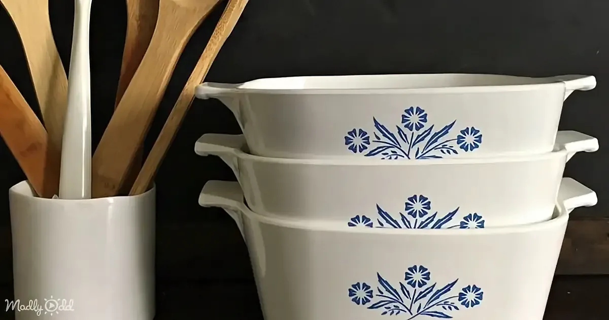 Stacked white baking dishes with blue floral patterns, wooden spoons in a white holder.
