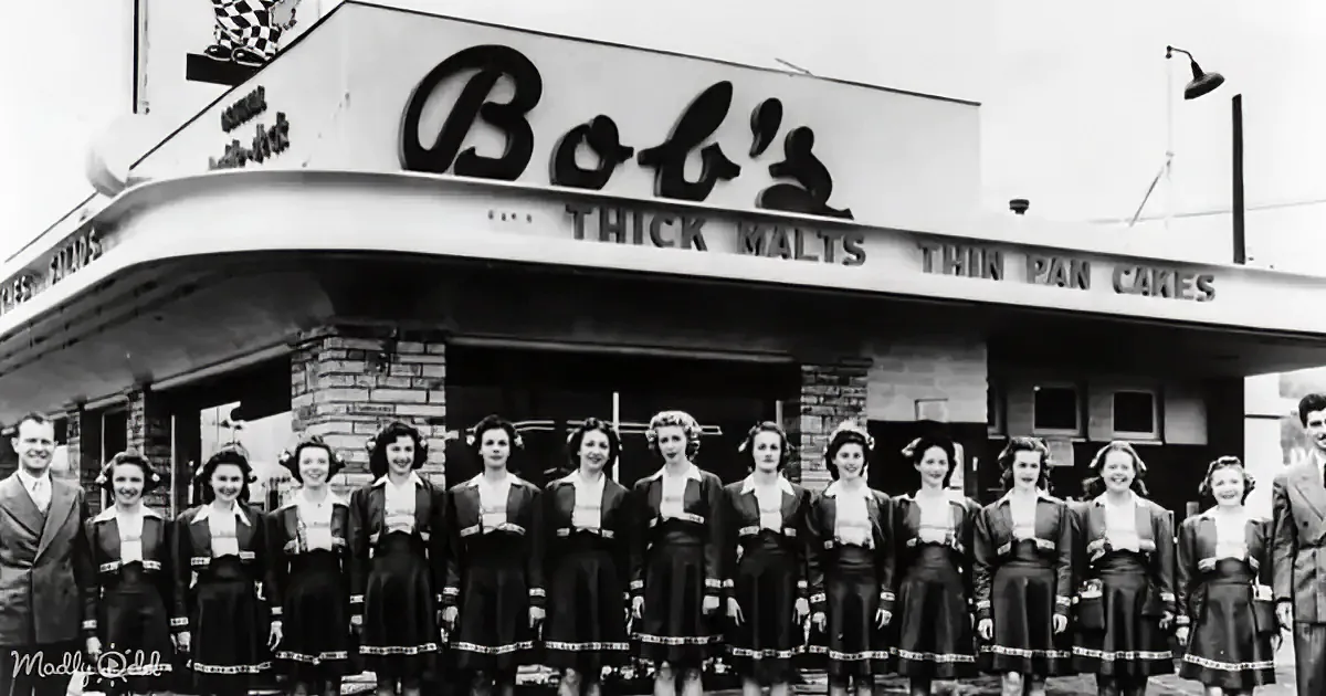 Women in uniform stand in front of Bob's restaurant, sign reads "Thick Malts Thin Pancakes."