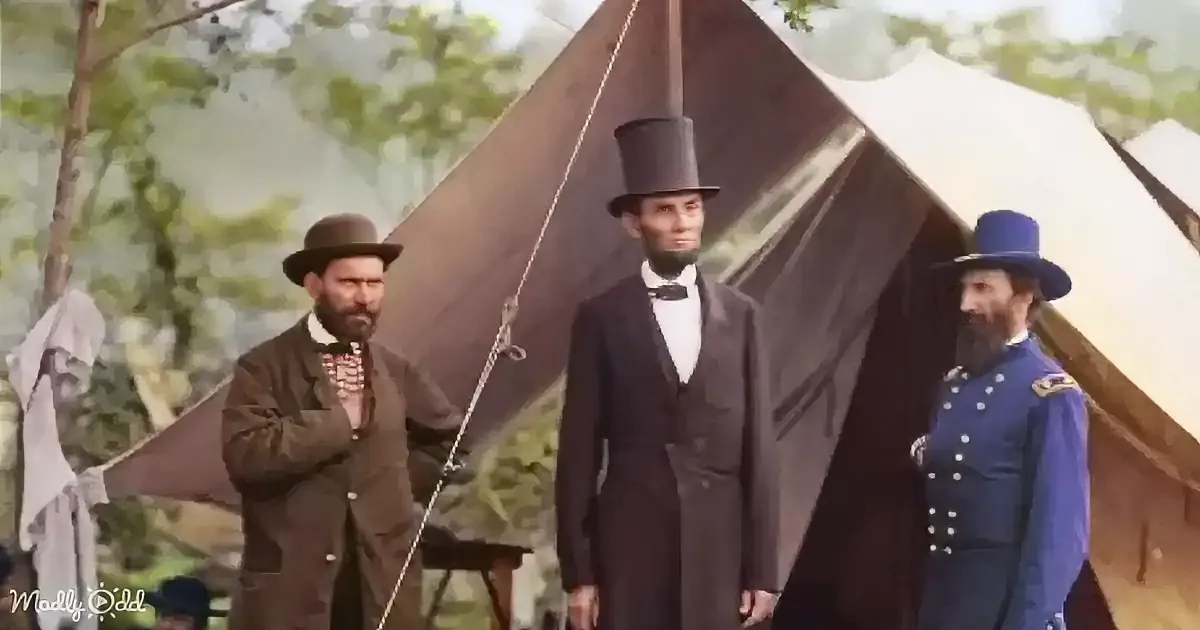 Abraham Lincoln in a top hat stands between two men in military uniforms near a tent.