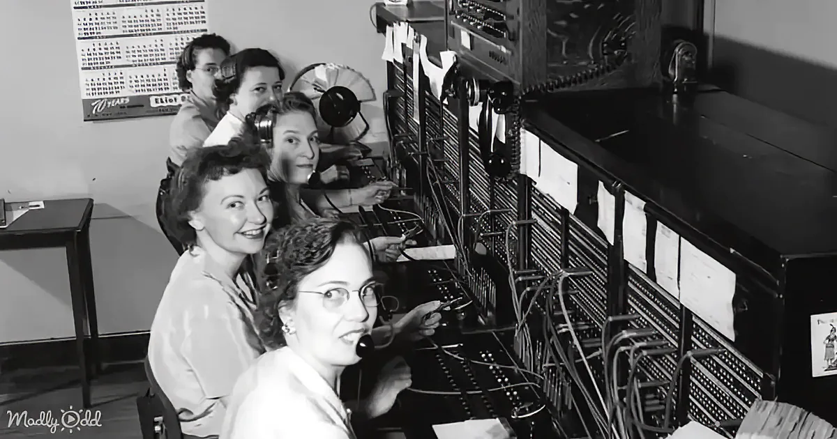 Women operate a vintage switchboard with cables and dials in a retro office setting.