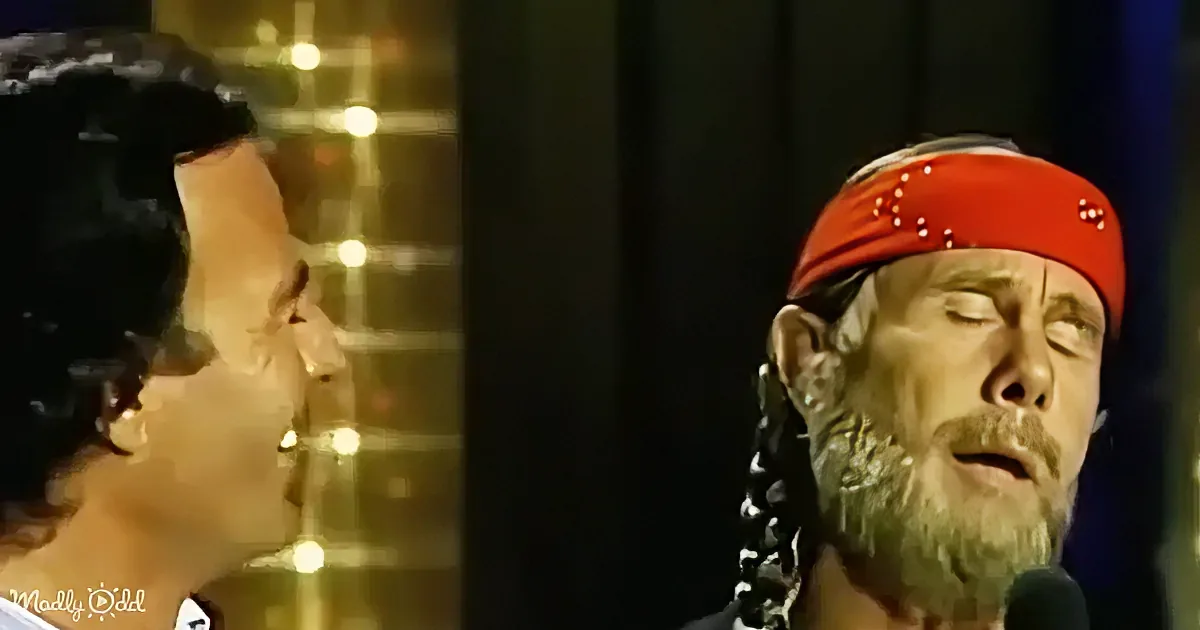 A man with a red bandana and braided hair looks to the side, while a woman with dark hair and a bow on her head looks up.