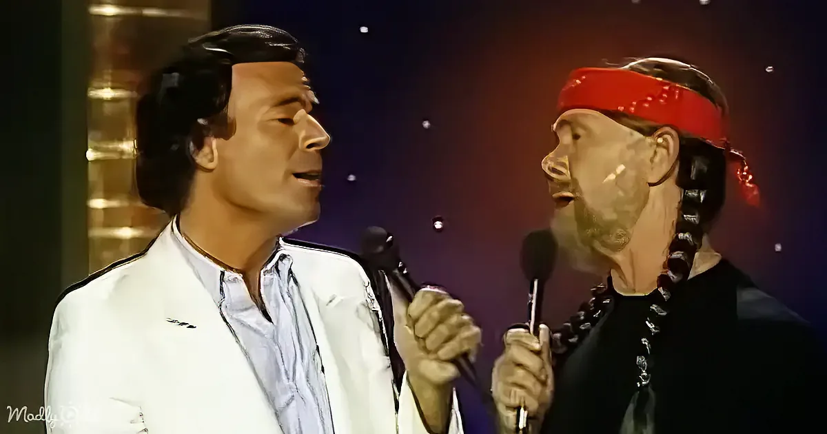 Two men, one in white, the other in black, holding microphones, singing on stage with a starry background.