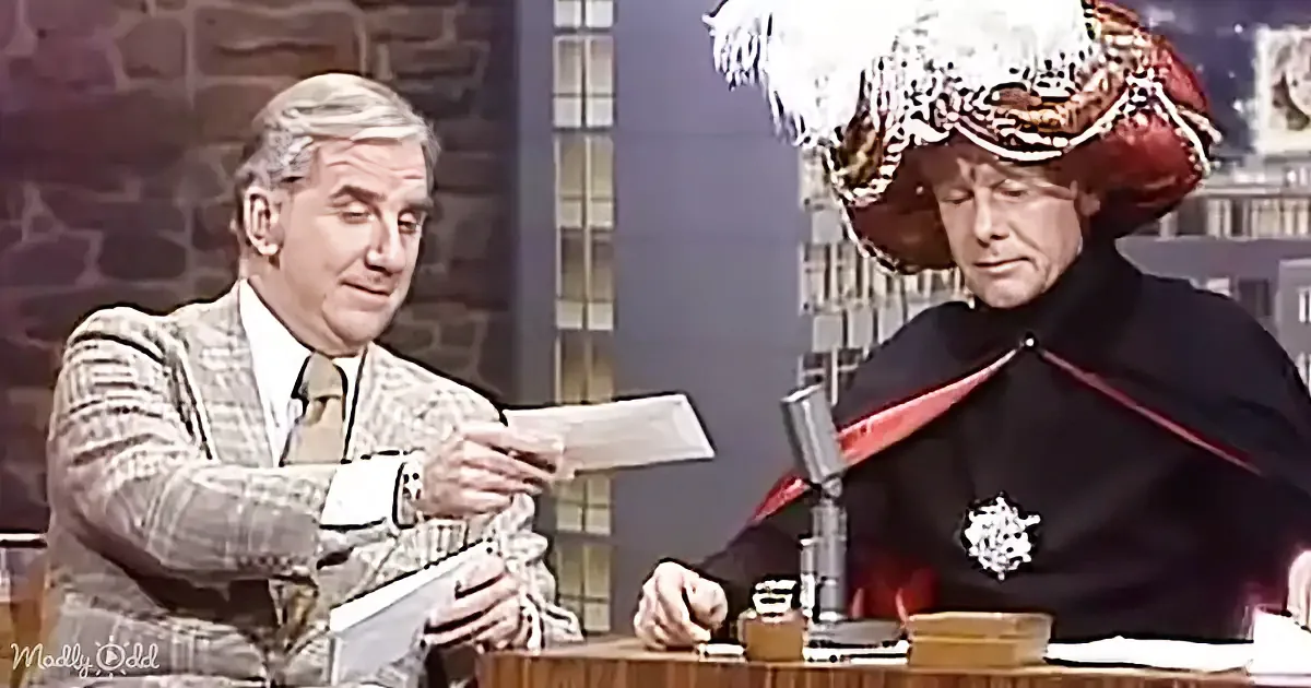 A man in a suit holds a piece of paper while another in a medieval costume listens intently.