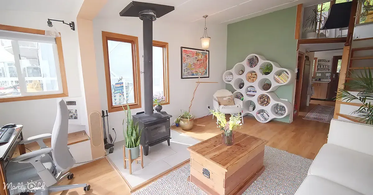 A cozy living room with a wood-burning stove, white furniture, and a bookshelf with circular shelves.
