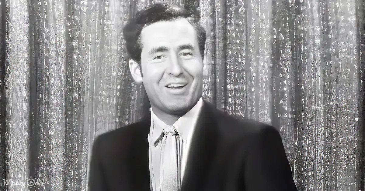 A man in a suit and tie smiles against a textured backdrop.