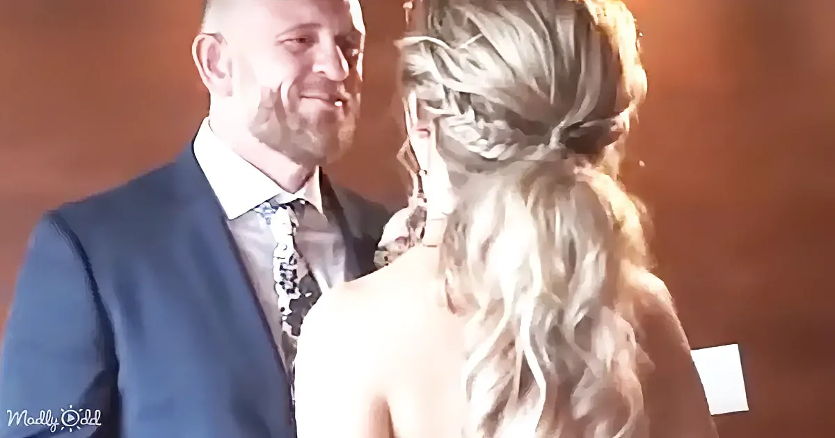 A man in a blue suit and patterned tie smiles at a woman with long, wavy blonde hair.