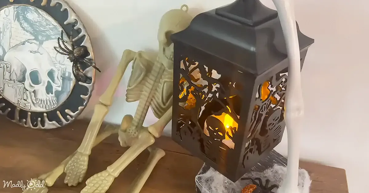 A spooky Halloween scene with a skeleton, a glowing lantern, and a skull plate with a spider.