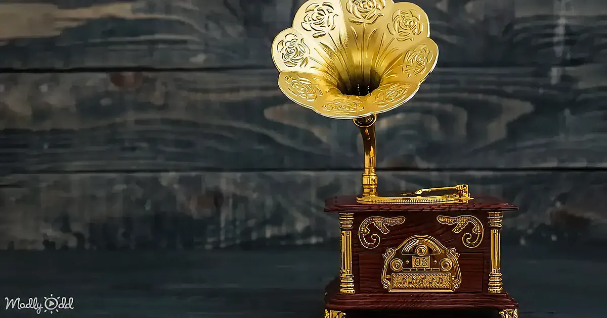 A golden gramophone with intricate designs sits atop a wooden base against a dark, textured background.