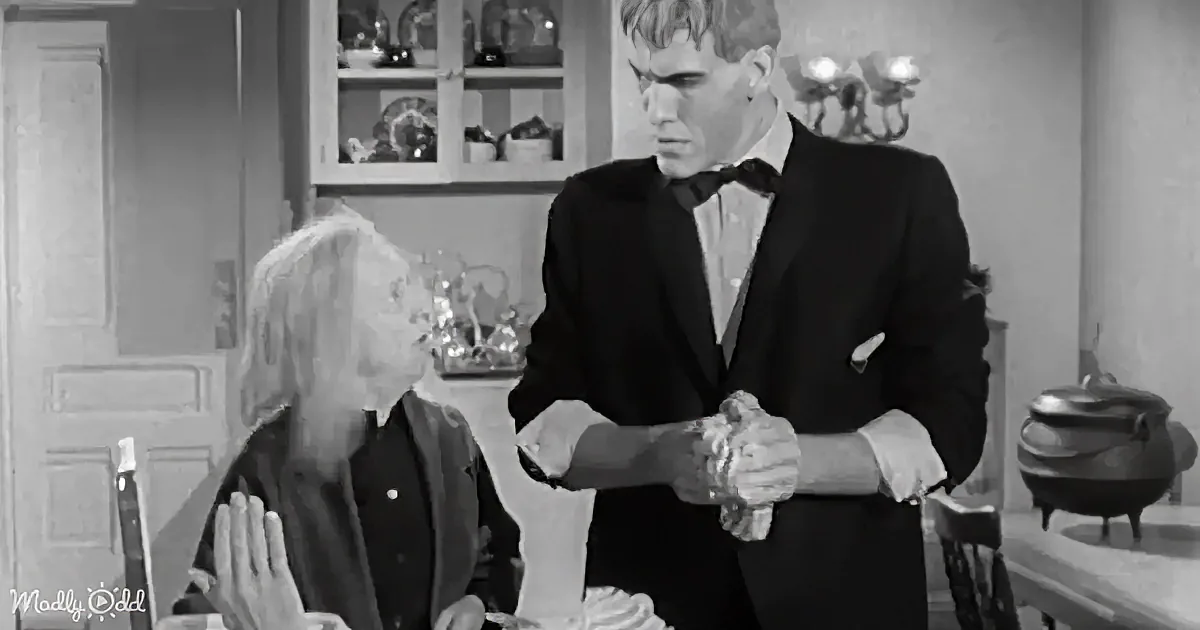A man in a tuxedo stands beside a seated woman, both focused on a cake in front of them.