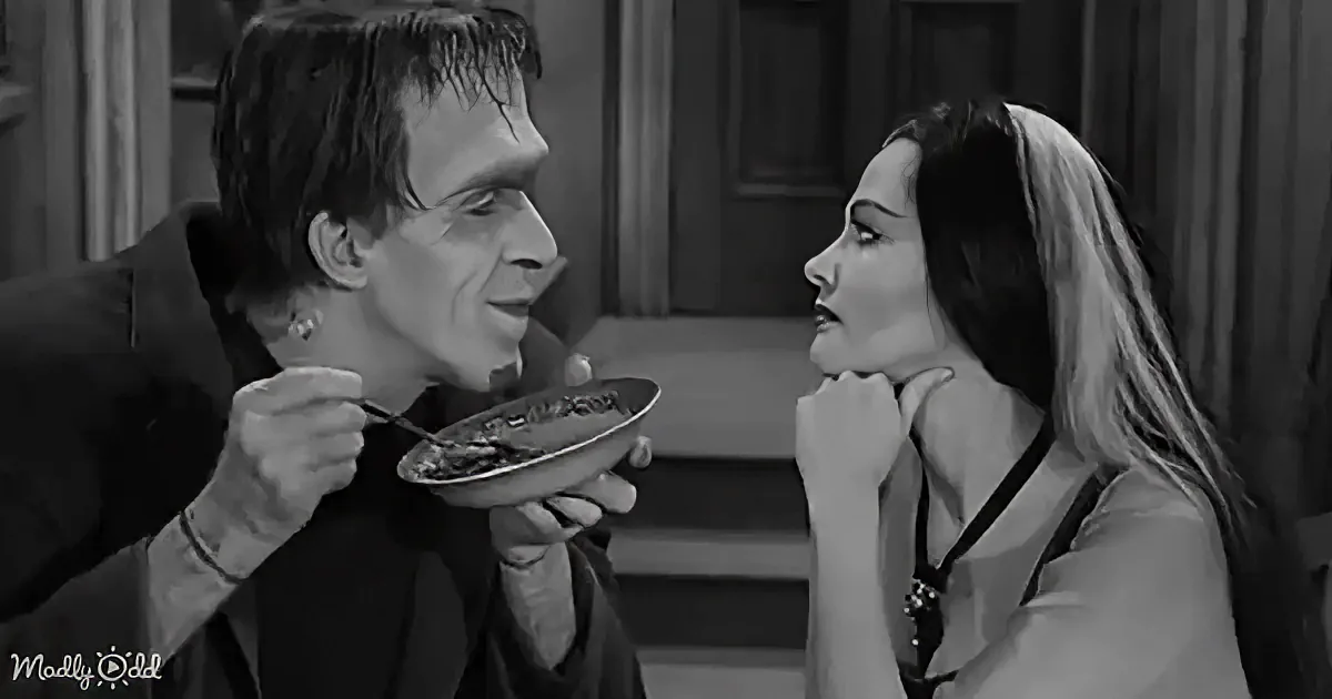 A man in a suit feeds a bowl to a woman with long hair, both in a dimly lit room.
