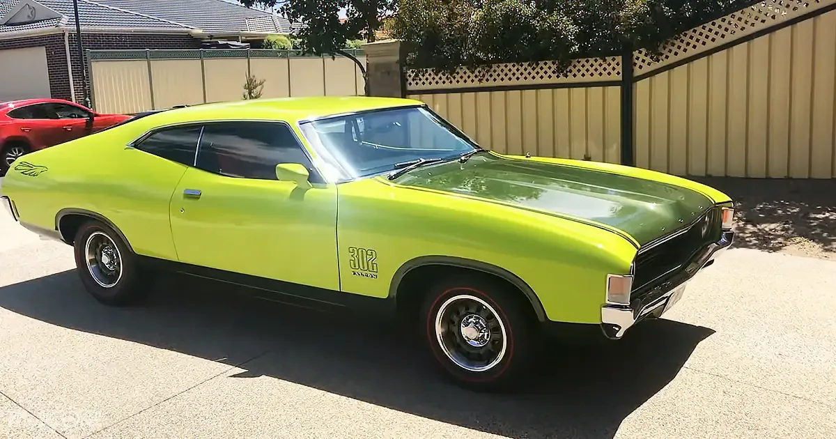 A bright green classic muscle car with "302" badge is parked in a driveway.