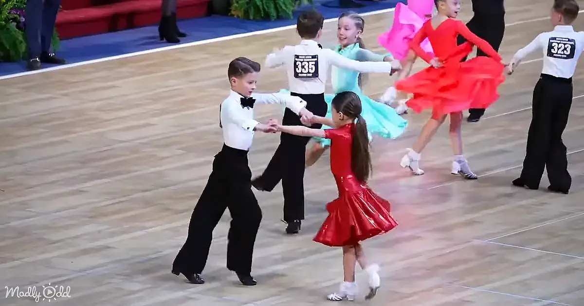 Children in formal attire dance in a line on a wooden floor, showcasing their skills.