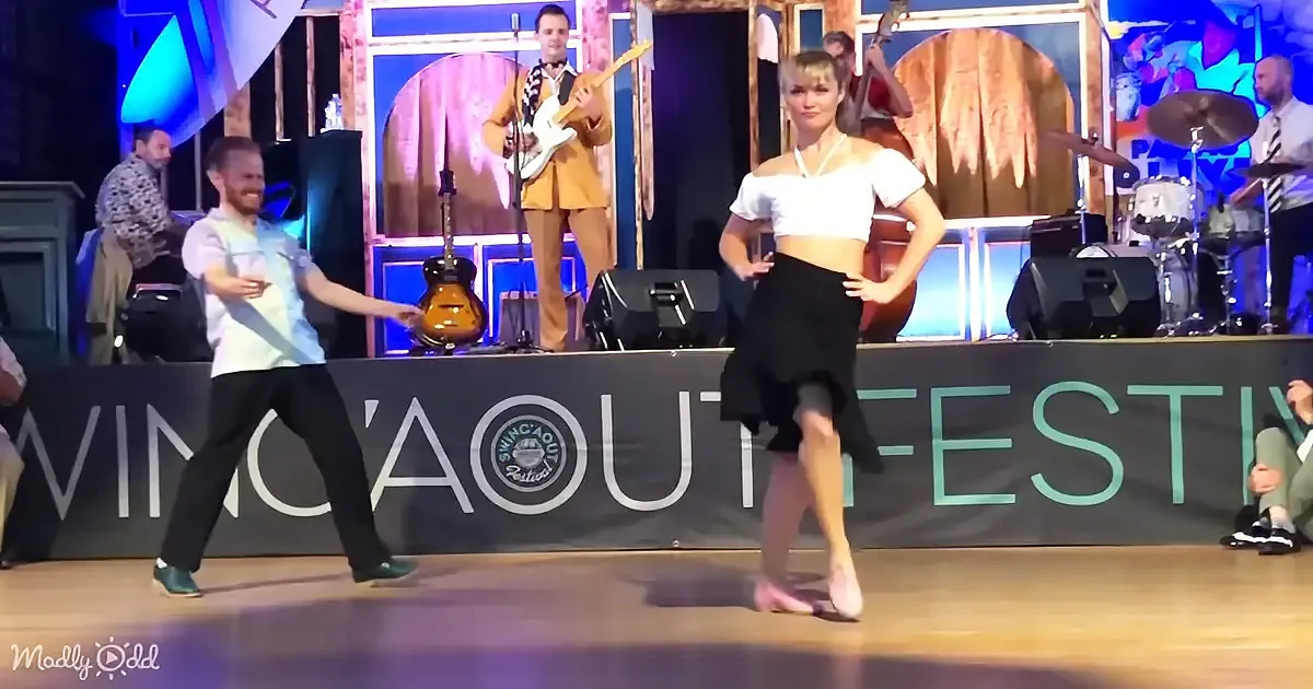 A man and woman dance on stage at the Swingin' Out Festival, with a guitarist and drummer in the background.