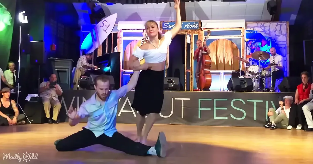 A man and woman perform a split dance move on stage at the Swing' Août Festival.