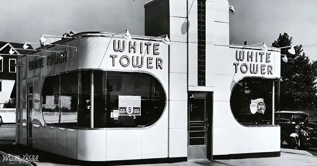 A vintage White Tower fast-food restaurant with retro signage and a classic car parked nearby.