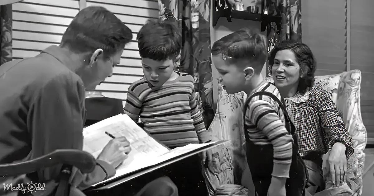 A man is writing on a clipboard while two boys and a woman watch attentively in a home setting.