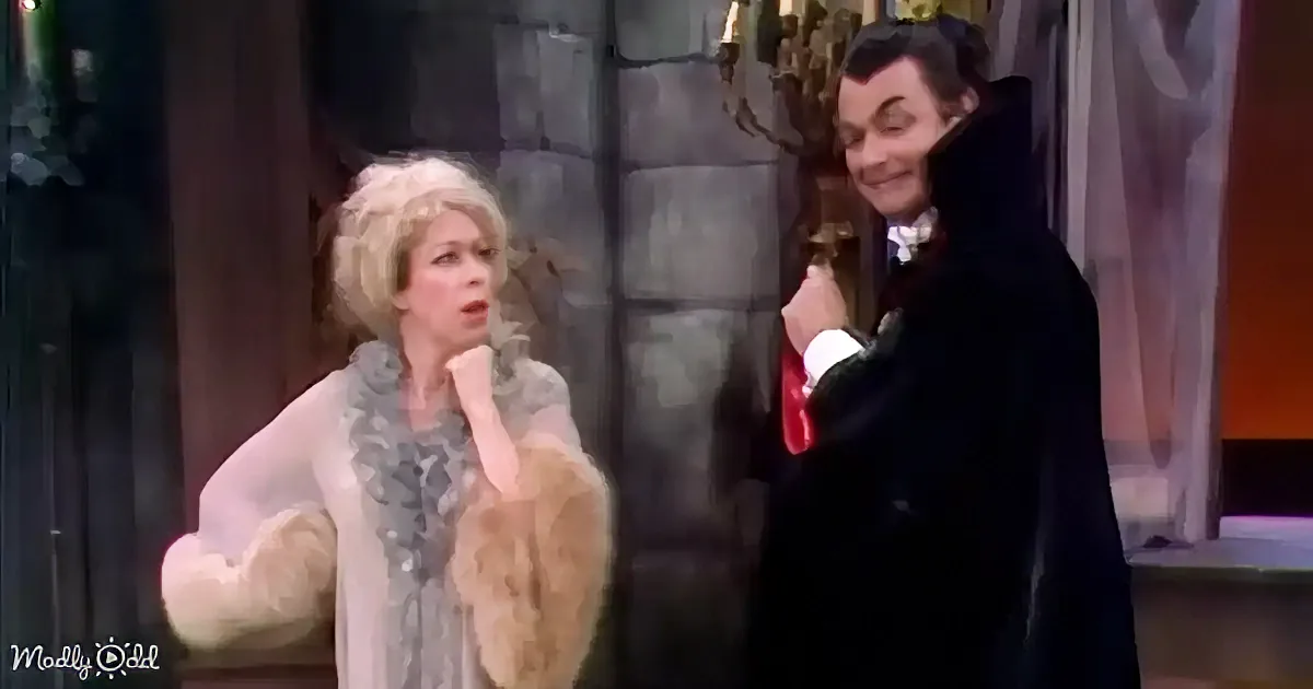 A woman in a fur coat and a man in a black coat are standing together, possibly in a theatrical or performance setting.