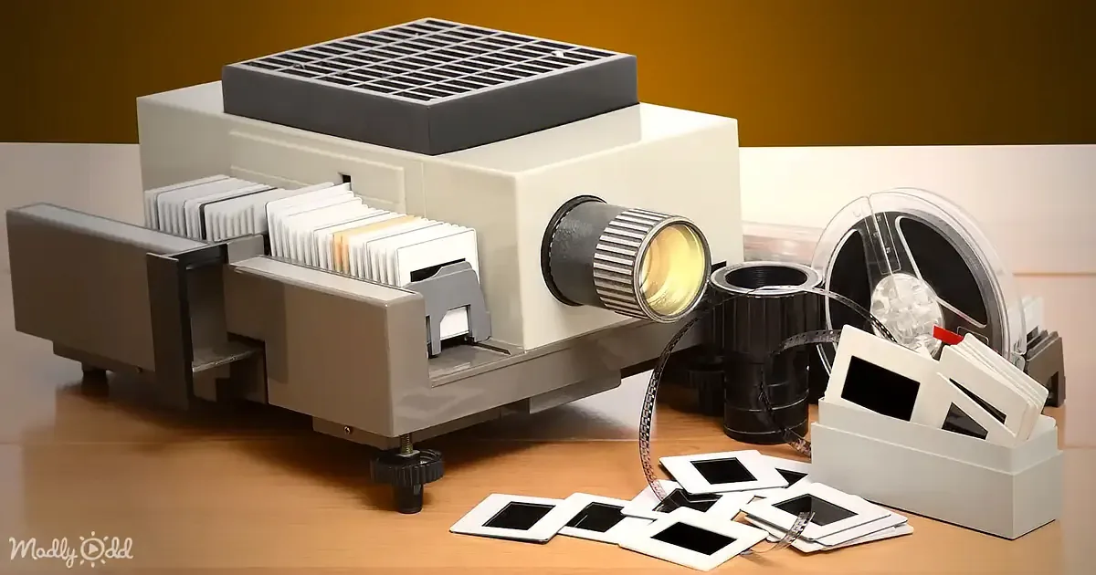 A slide projector with film reels and slides on a wooden table.