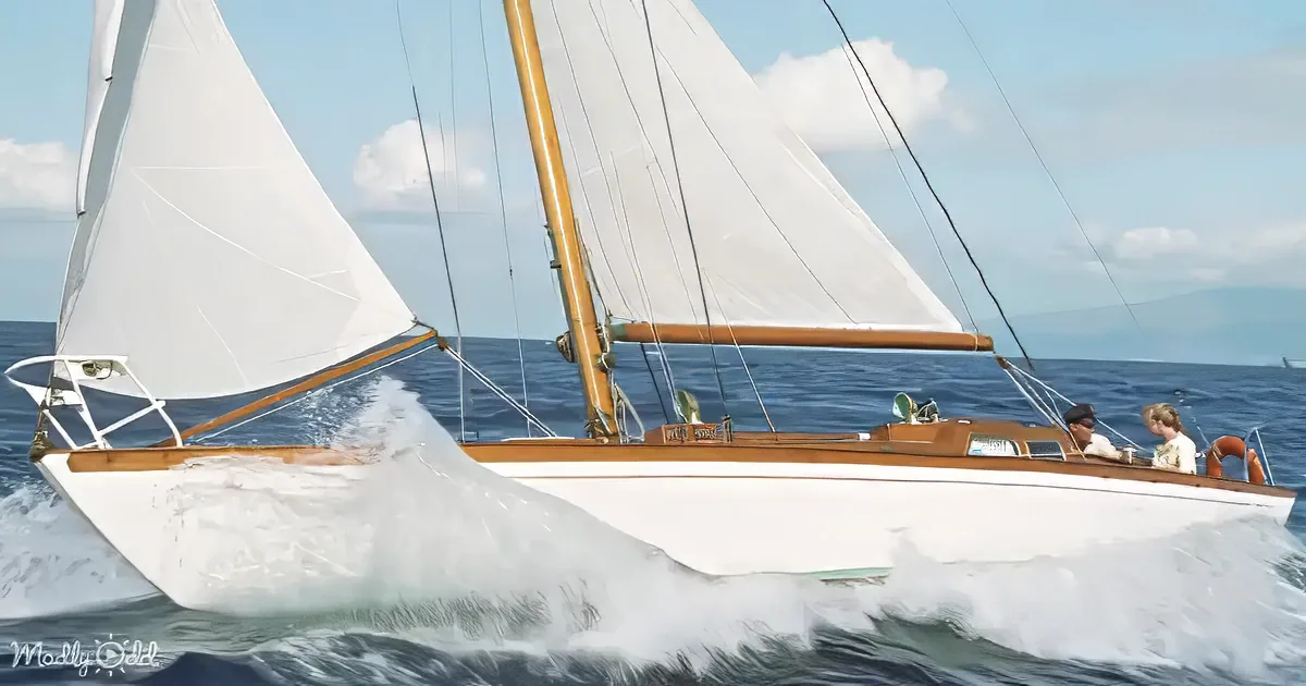 A sailboat with white sails and wooden trim cuts through the water, creating a splash.