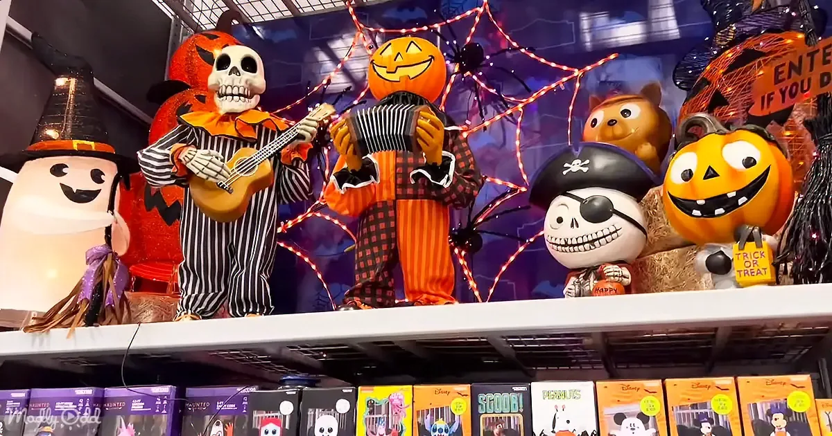 A Halloween display features skeletons, pumpkins, and a ghost playing instruments, with spooky decorations and "Trick or...